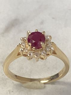 14kt Yellow Gold Lady's Diamond and Ruby Classic Halo Ring consisting of a 5mm round genuine Ruby with deep red color and tone 1/2ct approx. total weight prong set surrounded by accent diamonds .12ct total weight all prong set in solid heavy mounting in finger size 5 3/4. This ring can be resized for an additional $95.00 upon request. This item would Retail for $1,275.00 Classic Red Ruby Cluster Ring, Classic Red Cluster Ruby Ring, 14k Gold Red Cluster Ring With Brilliant Cut, Red Cluster Diamond Ring In 14k Gold, Red Diamond Cluster Ring In 14k Gold, Gold Ruby Cluster Ring With Halo Design, Classic Red Cluster Ring, Classic 14k Gold Ruby Ring With Halo Design, Red Brilliant Cut Birthstone Ring In 14k Gold