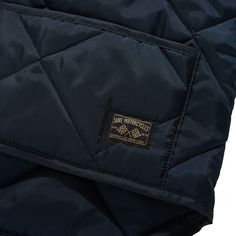 the quilted jacket is black and has a gold patch on the front, along with a white background