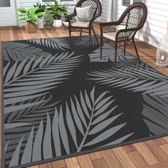 a black and white rug with palm leaves on it in front of a porch area