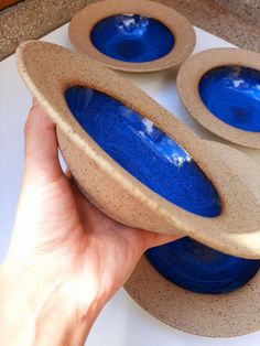 a person holding two blue bowls in their hand