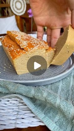 a piece of bread sitting on top of a plate next to a person's hand