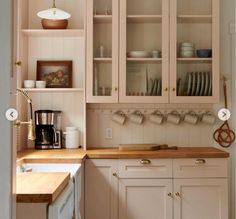 a kitchen with white cabinets and wooden counter tops, along with an open shelf above the sink