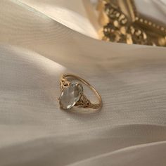 a gold ring with an aqua blue topazte sits on a white satin surface