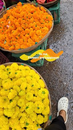 there are many baskets with flowers in them on the street and someone is standing next to it