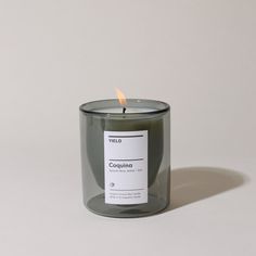 a candle with a label on it sitting in front of a white wall and floor