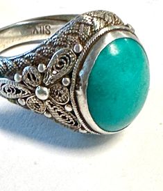 Silver Chinese export ring, vintage(circa 1950s) It is adjustable presently a 6 1/2 but could be 1 s size up or down.  Hand wrought extremely find filigree and woven wire setting.  Lovely genuine bezel set cabochon 14mm by 11mm. Antique Adjustable Rings With Intricate Design, Vintage Oval Turquoise Ring For Formal Events, Antique Turquoise Gemstone Ring For Formal Occasions, Vintage Oval Turquoise Ring For Formal Occasions, Vintage Filigree Ring Jewelry, Vintage Cabochon Emerald Ring For Anniversary, Vintage Turquoise Gemstone Ring For Formal Occasions, Vintage Turquoise Ring For Formal Occasions, Vintage Adjustable Filigree Ring For Formal Occasions