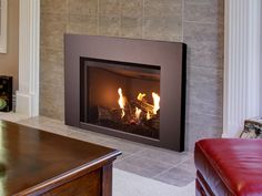 a living room with a fire place in the center and a red leather chair next to it