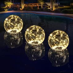 three lighted balls sitting on top of a pool