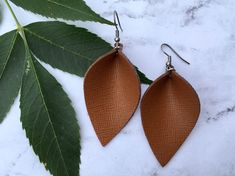 These leather pinched earrings are a lovely camel tan colour!  The leather has a linen like print on it adding texture and interest!  The leather is a genuine leather that is great quality strong and sturdy and will last.  These earrings are lightweight you won't even feel them on!   A choice of two sizes the medium teardrop measures 2.25 inches in length by 1.5 inches at the widest.  The large teardrop measures 1.75 inches at widest and 2.8 inches in length.   Featuring stainless steel nickel free ear wire. (Photos is of medium) Join our facebook group Glitter and Leather Co VIP for sneak peaks, discounts and giveaways! Follow us on Instagram:  Instagram.com/glitterandleatherco Glitter and Leather Co is handmade jewelry line by Anita Recksiedler.  Featuring easy to wear lightweight earrin Elegant Brown Leather Earrings, Handmade Brown Faux Leather Earrings, Brown Leather Earrings, Brown Drop Earrings For Everyday Use, Casual Handmade Brown Earrings, Casual Brown Handmade Earrings, Brown Drop Earrings For Everyday, Everyday Brown Drop Earrings, Leather Leaf Earrings