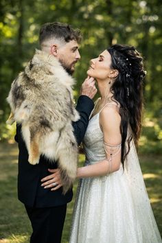 a bride and groom are standing in the woods with their fur stole around their necks