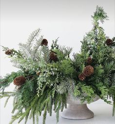 a vase filled with pine cones and greenery