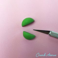 two green pieces of plastic sitting on top of a pink surface next to a pair of scissors