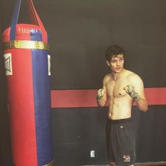 a young man standing next to a punching bag