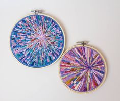 two hand embroidered hoop art pieces on a white surface, one with blue and pink colors