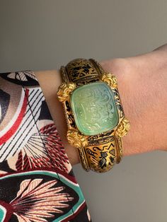 "This exquisite  archeological-revival bangle is attributed to Robert Phillips, circa 1865. The hinged bangle is decorated with Egyptian hieroglyphs in glossy black enamel culminating in a jade intaglio with a covered compartment to the reverse. \"ذات تو مظهر انعام سبحانی باد\", written in Farsi, it translates to, \"May your essence be a manifestation of divine blessings.\" A beautiful sentiment of well-wishing and hope for a positive and spiritually enriched existence. Hand fabricated in 15 karat gold, this bangle fits a petite 6\" wrist. A rare and wonderful jewel.    Weight: 28.1 grams Markings: none  Measurements: 6\" interior circumference, 1\" widest point (face) Notes: some losses to the enamel as shown" Traditional Ceremonial Intaglio Jewelry, Luxury Engraved Bracelets For Ceremonial Occasions, Luxury Ceremonial Bangle Bracelets, Traditional Jewelry With Historical Design For Collectors, Luxury Ceremonial Bangle With Intricate Design, Luxury Engraved Bangle For Ceremonial Occasions, Antique Intaglio Ceremonial Jewelry, Antique Intaglio Jewelry For Ceremonial Occasions, Antique Ceremonial Intaglio Jewelry