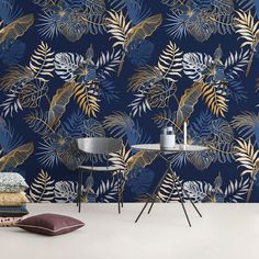 a blue and gold tropical wallpaper with palm leaves on the side, next to two chairs