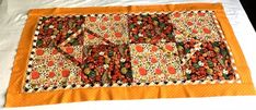 an orange and white quilted placemat on a bed