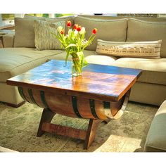 a wooden table with flowers in a vase sitting on it's end next to a couch