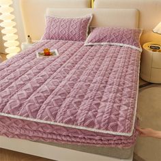 a bed with pink bedspread and matching pillows