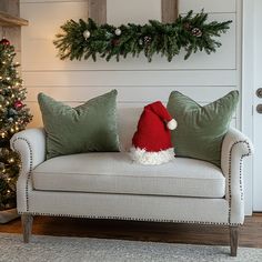 a white couch with green pillows and a santa hat on it