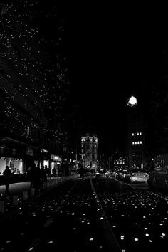 people are walking down the street at night with stars on the ground in the dark