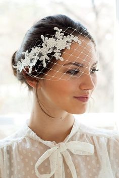 a woman wearing a veil and headpiece with white flowers on the top of it