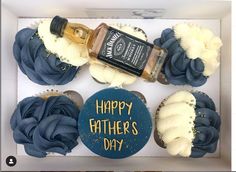 cupcakes in a box decorated with blue icing and white frosting, topped with a bottle of whiskey