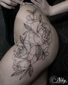 a woman's thigh with roses and leaves tattoo on the side of her leg