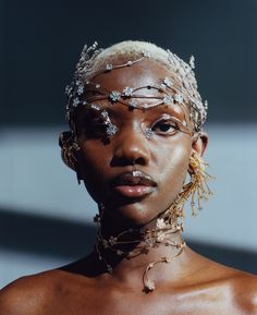 an african woman with gold jewelry on her head and chest, looking off to the side