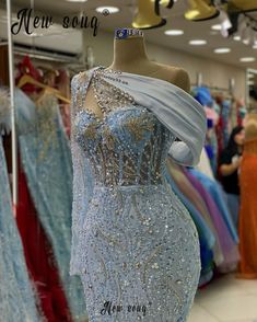 a dress on display in a store with other gowns and dresses for sale behind the mannequin