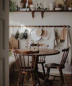 a dining room table and chairs in front of a wall with plates hanging on it