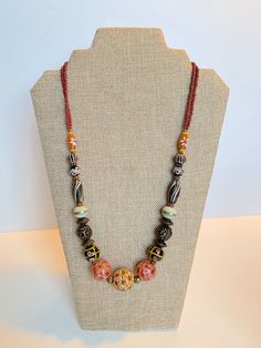 Stunning Handmade Dayak (Borneo) Beads Necklace. Hand painted beads with different color tone.  The unique and meticulous patterns inscribe on each bead. Hailing all the way from the island of Kalimantan in Indonesia, these beads are carefully handcrafted using the finest materials including carnelian, crystal, clay and other natural stone.  In the same way each stroke of red, yellow and blue paint depicts the unequivocal talents of the craftsman. Bohemian Czech Glass Oval Beads, Bohemian Oval Czech Glass Beads, Bohemian Czech Glass Polished Beads, Traditional Czech Glass Beaded Necklaces, Brown Polished Beads For Beach, Hand-strung Multicolor Round Beaded Necklaces, Artisan Hand-strung Double Strand Beaded Necklaces, Artisan Double Strand Beaded Necklaces, Bohemian Czech Glass Spacer Beads