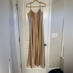 a tan dress hanging on a white door