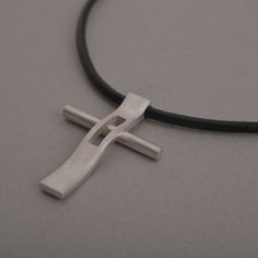 "Rejoice in your commitment to the faith with this modern cross necklace. Wear your Christianity with pride and show the world the beauty that lies within each time you get dressed. This modern cross necklace is custom handmade in majestic detail from sterling silver. Polished to a brilliant shine, it is suspended from a length of black leather cord to complete the look. It makes a fabulous gift and will be a heartwarming addition to his existing jewelry collection. Cross measures 3.4 cm x 2.5 c Modern Crucifix Cross Necklace As Gift, Modern Crucifix Necklace As Gift, Modern Cross Pendant Necklaces As Gift, Modern Necklaces With Cross Pendant For Gift, Modern Necklaces With Cross Pendant As Gift, Modern Stainless Steel Cross Necklace For Gift, Modern Stainless Steel Cross Pendant Necklace, Modern Cross Necklace As A Gift, Modern Stainless Steel Cross Jewelry