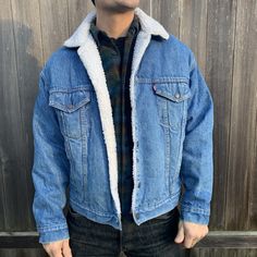 "This denim jacket is warmly lined in the most classic Levi style. Very well made by Levi in the USA, the jacket is in great condition. Beautiful metal buttons complete this men's size large button up. White synthetic shearling has been kept very clean. Jacket is men's sizing but is a unisex design. -Model size women's medium/large. -Model size men's large. Approximate measurement when laid flat: 25\" armpit to armpit 22\" shoulder to shoulder 23\" sleeve 25\" back of collar to hem" Winter Outdoor Denim Jacket With Pockets, Winter Denim Jacket With Pockets For Outdoor, Medium Wash Denim Jacket For Winter Outdoor, Winter Outdoor Dark Wash Denim Jacket, Classic Outdoor Denim Jacket With Pockets, Classic Denim Jacket For Outdoors, Denim Blue Outerwear For Outdoor Winter Activities, Winter Denim Outdoor Outerwear, Winter Outdoor Denim Outerwear