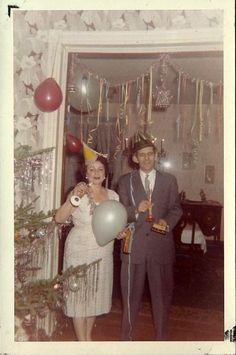 a man and woman standing next to each other in front of a doorway with balloons