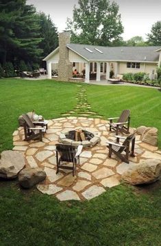 a fire pit in the middle of a lawn with chairs around it and a house in the background