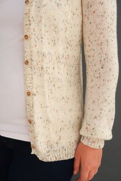 a close up of a person wearing a white cardigan sweater with buttons on it