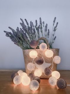 a basket filled with lots of lights sitting on top of a wooden table next to a plant