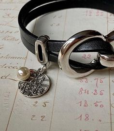 A feminine, silver floral charm with pearl hangs delicately near the clasp of this leather wrap bracelet for women. When leather meets pearl, a timeless combination is born! Youll see a close-up of the cute floral charm in the photo scroll. The photos show the dark gray leather (which has a subtle Charm Bracelet Silver, Pearl Charm Bracelet, Feminine Jewelry, Boho Wrap Bracelet, Handmade Leather Bracelets, Red Moon, Beaded Wrap Bracelets, Wrap Bracelets, Pearl Leather