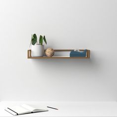 an open book on a shelf with two plants and a potted plant next to it