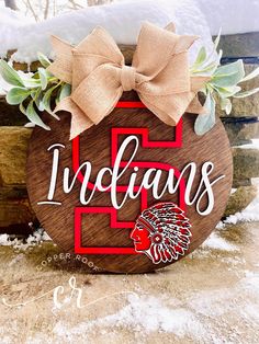 a wooden sign with the word indians on it and a bow in front of some snow