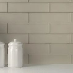 three white canisters sitting on top of a counter next to a brick wall