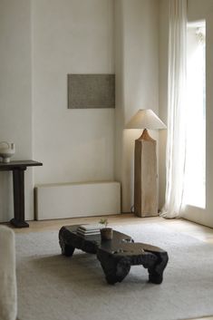 a living room with a coffee table on the floor and a lamp next to it