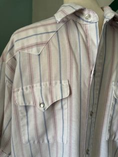 True vintage 70s 80s Panhandle Slim country western pearl snap shirt. Short sleeved white with pink and blue stripe. Made in USA. No stains. Note shirt tail edge as pictured. Size 17 1/2. Spring Americana Long Sleeve Tops, Western Style Cotton Shirt For Spring, Spring Rodeo Button-up Shirt, White Western Button-up Top, Western Style Shirt For Ranch In Spring, Western Shirt For Spring Ranch Occasions, Western Style Shirt For Spring Ranch, Summer Pinstripe Shirt With Button Closure, Spring Ranch Button-up Shirt