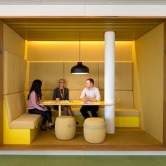 two people sitting at a table in a room with yellow walls and benches on the floor