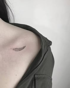 the back of a woman's shoulder with a feather tattoo on her left shoulder