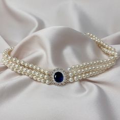 I took the inspiration for this pearl choker from Princess Diana's 18th birthday present from the Spencer's, this vintage sapphire necklace is a 3 strand faux pearl choker which will give you an exquisite layered necklace look. With a stunning sapphire stone set in a round bed of crystals taking centre of the choker.  This pearl choker necklace was beautifully handmade and will come in a organza bag inside a Lovett & Co pillow pack, perfect to give as a gift or to keep. We can offer a personalised message service for FREE, we will print it onto one of our beautiful vintage style postcards for you.  What would you like to say? 🤍Hypoallergenic  🤍Nickel Free Matching items available.  shorturl.at/mIJWY shorturl.at/ixPY2 Length: 30cm  With a 12cm adjuster chain. Width: 2cm Pearl Necklace With Brooch, Princess Necklace Jewellery, Princess Diana Pearl Necklace, Diana Jewellery, 18th Birthday Present, Diana Necklace, Princess Diana Jewelry, Sapphire Brooch, Best Jewellery Design