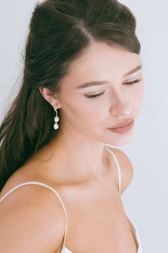 a woman in a white dress with her eyes closed and one ear dangling from the side