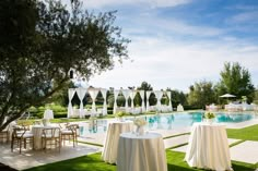 an outdoor dining area with tables and chairs next to a swimming pool in the background